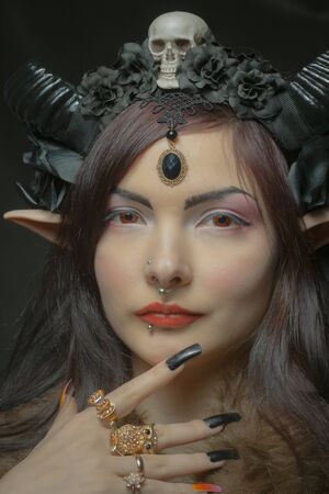 Pretty girl with horns and elvish ears posing over dark