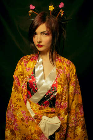 Pretty geisha in kimono posing over dark background