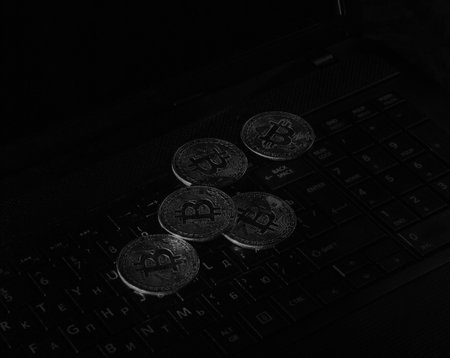 Bitcoins laying on a laptop keyboard in neon lightsの写真素材