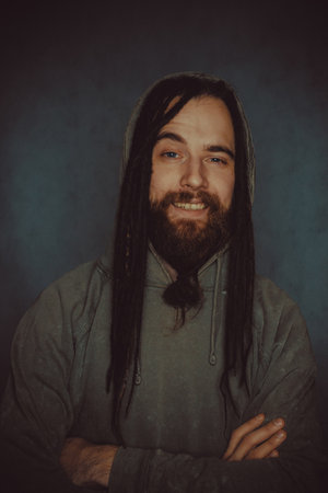 Young bearded man posing in hoodie over grey backgroundの写真素材