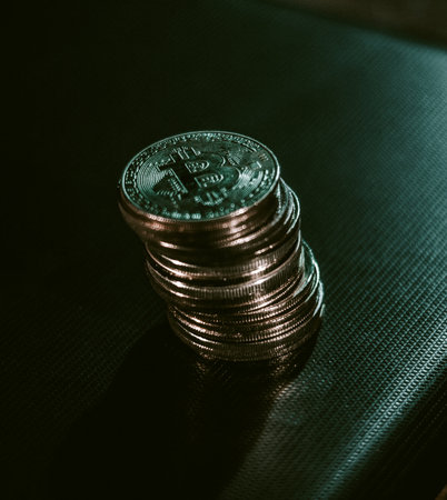 Stack of bitcoins over dark surface in neon lights