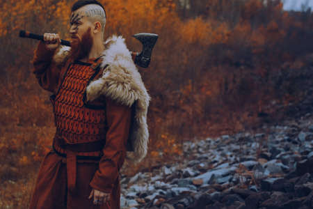 Brutal scandinavian warrior with axe posing outdoorsの写真素材