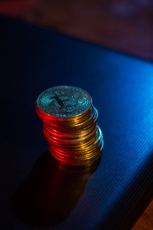 Stack of bitcoins over dark surface in neon lightsの写真素材