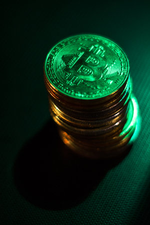 Stack of bitcoins over dark surface in neon lightsの写真素材