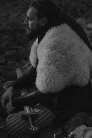 Scandianvian warrior armed with sword sitting on a river coastの写真素材