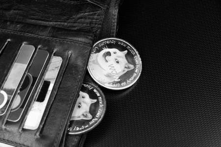 Open male brown leather wallet with dogecoins on a dark surface.の写真素材