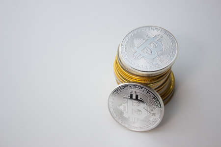 One silver bitcoin and stack of bitcoins over white background