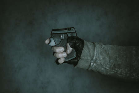 Self defense weapon in a hand. Pepper aerosol pistol over dark background.