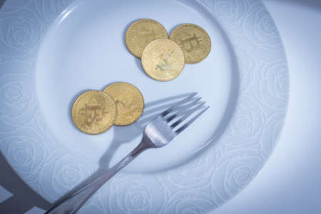 BItcoins and fork in plate over white backgroundの写真素材
