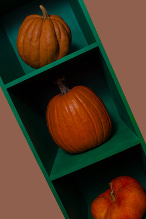Three pumpkins on a green shelvesの写真素材