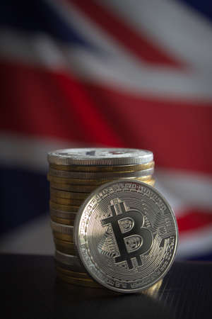 Stack of bitcoins over flag of the United Kingdom. Focus on bitcoins.の写真素材