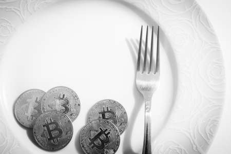 Bitcoins with fork  in plate over white backgroundの写真素材