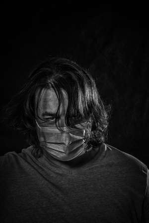 Man wearing medical mask over dark backgroundの写真素材