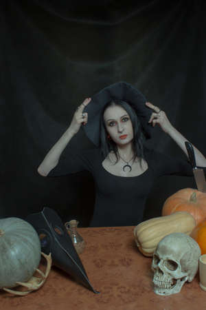Pretty girl in witch hat posing over dark background