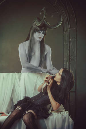 Horned demon trying to touch innocent gothic girl