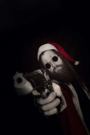 Bad Santa Claus with gun over dark backgroundの写真素材