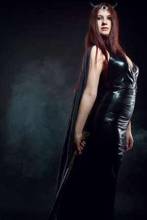 Attractive horned woman with sword over dark backgroundの写真素材