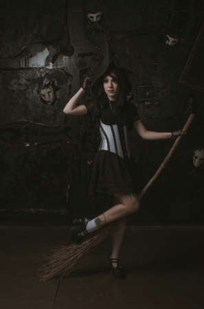 Woman with witch hat and broom posing at photo studioの写真素材