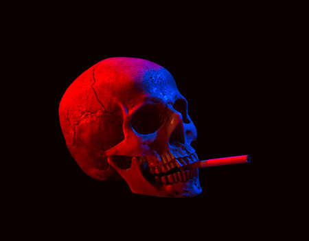 Human skull  with cigarette isolated over dark backgroundの写真素材