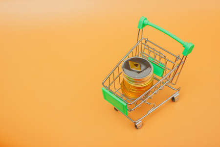 Toy shopping cart with ethereum coins over yellow backgroundの写真素材