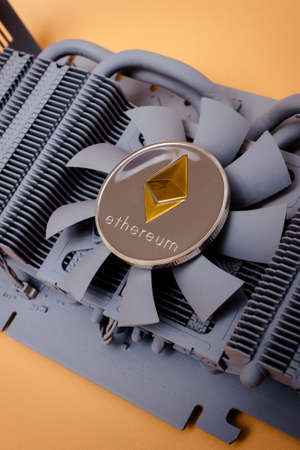 One ethereum coin over graphic videocard over yellow background