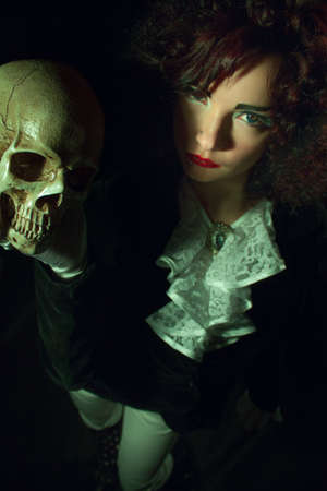 Gothic girl with skull over dark background