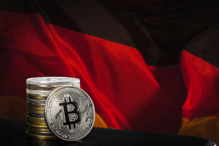 One silver bitcoin and stack of bitcoins over german flagの写真素材