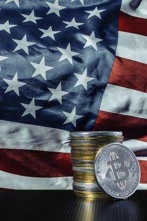 One silver bitcoin and stack of bitcoins over USA flagの写真素材