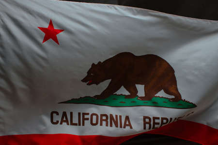 Waving California state flag over dark background