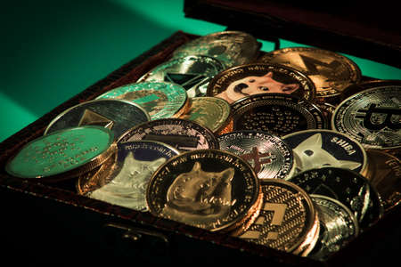 Pile of cryptocurrencies in a chest over green backgroundの写真素材