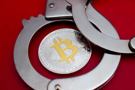 Bitcoin and handcuffs over red backgroundの写真素材