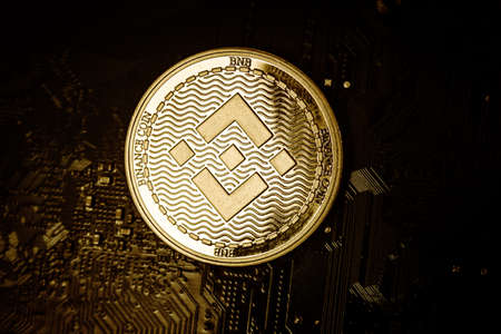 Closeup shot of one golden binance coin over motherboardの写真素材