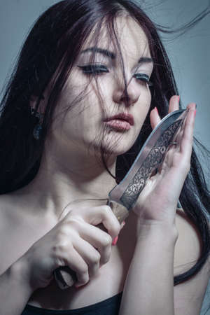 Cute asian girl with knife over grey background