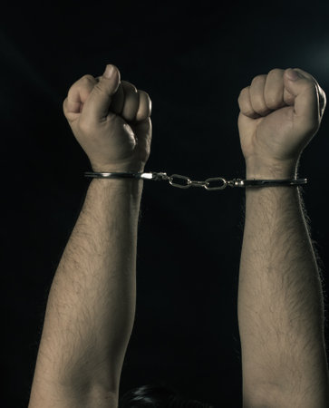 Male hands in handcuffs over dark background