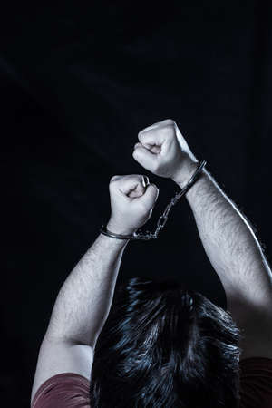 Male hands in handcuffs over dark background
