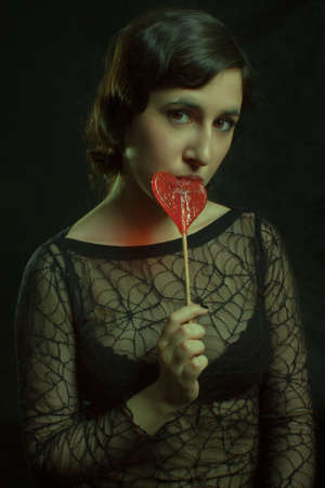 Portrait of young sexy woman with candy over dark backgroundの写真素材