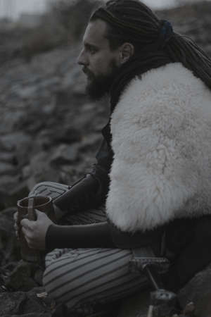 Scandinavian warrior armed with sword sitting on a river coastの写真素材