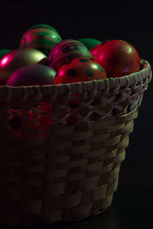 Painted easter eggs in basket over dark backgroundの写真素材