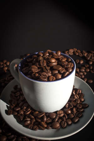 Cup full of coffee beans over black backgroundの写真素材