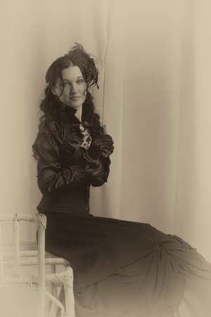 Old fashioned lady in black sitting on vintage chair