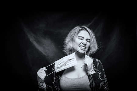 Young beautiful woman posing with medical mask over dark background