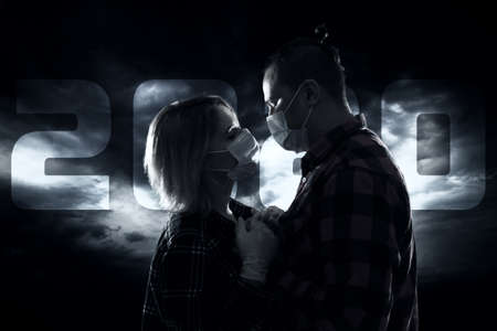 Young couple in masks over dramatic skyの写真素材