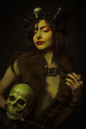 Horned girl posing over dark background with skull