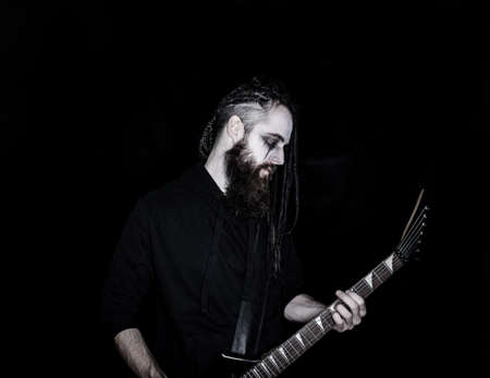 Brutal guitarist with black guitar over dark backgroundの写真素材
