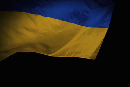 Close-up shot of waving ukrainian flag over black background