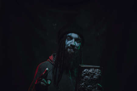 Bearded man with witch book posing over dark background