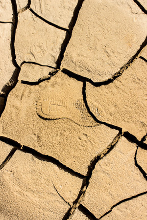 Close-up of footprint on dry cracked barren landの写真素材