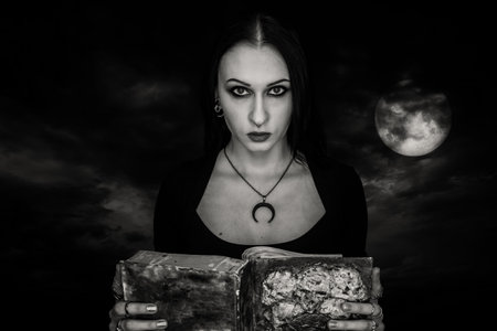 Gothic girl wih spell book over dramatic night sky.の写真素材