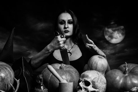 Gothic girl posing with pumpkins over dramatic sky.の写真素材