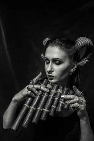 Horned faun with panflute posing over dark backgroundの写真素材